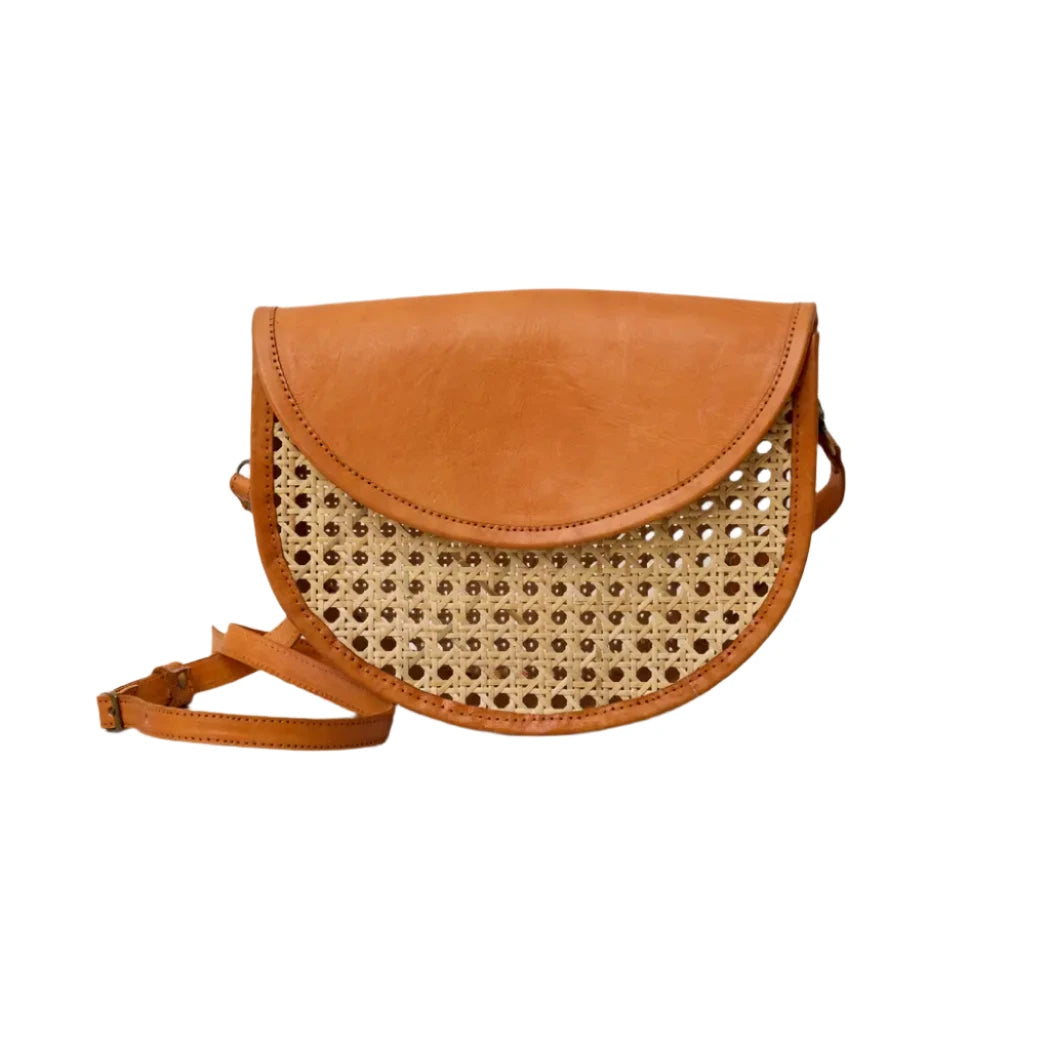Half-circle crossbody bag with a woven rattan cane front panel, genuine leather trim, fold-over flap, and adjustable leather strap