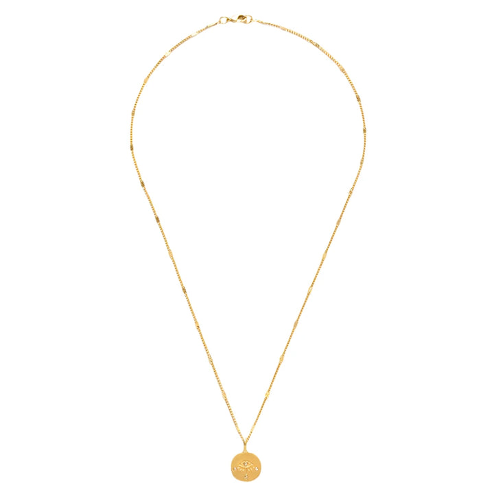 A gold Eye of Protection Necklace featuring a round pendant with an engraved eye design and crystal accents. The pendant hangs from a delicate gold chain with subtle decorative links,