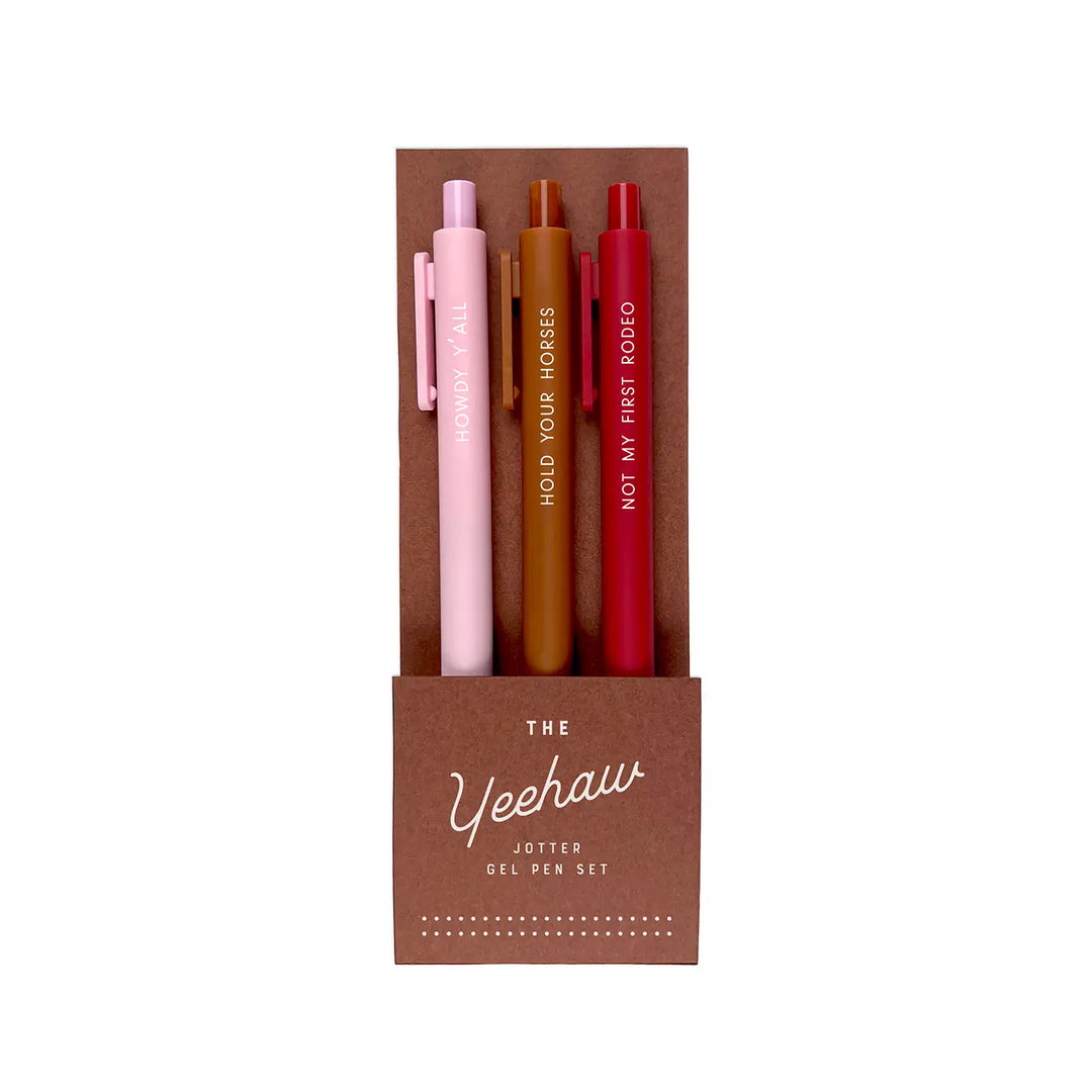Set of three gel pens in shades of pink, brown, and red with Western-themed phrases in a brown box labeled “The Yeehaw Jotter Gel Pen Set.”