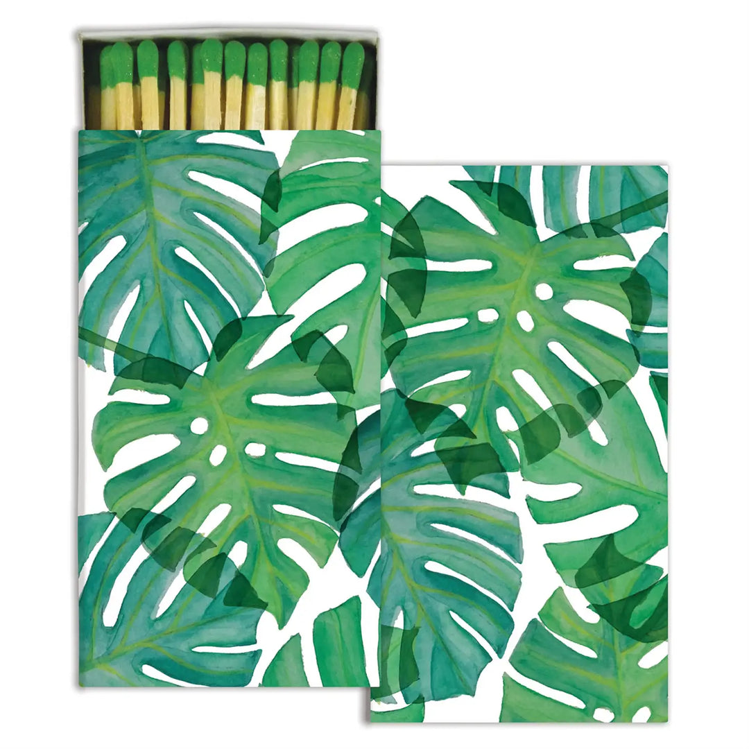 White box of matches that features green monstera leaves.