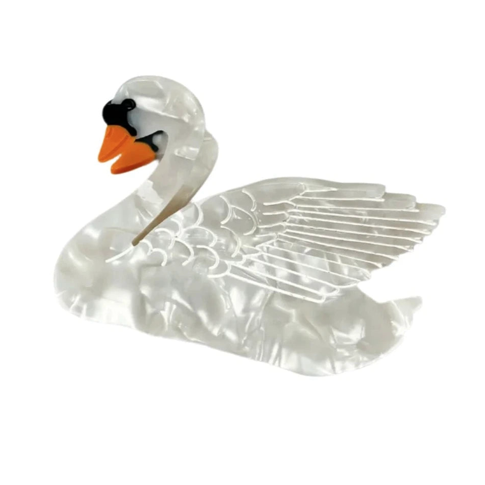 A swan-shaped hair clip with a pearlescent white finish, detailed wings, and an orange beak, set against a white background.