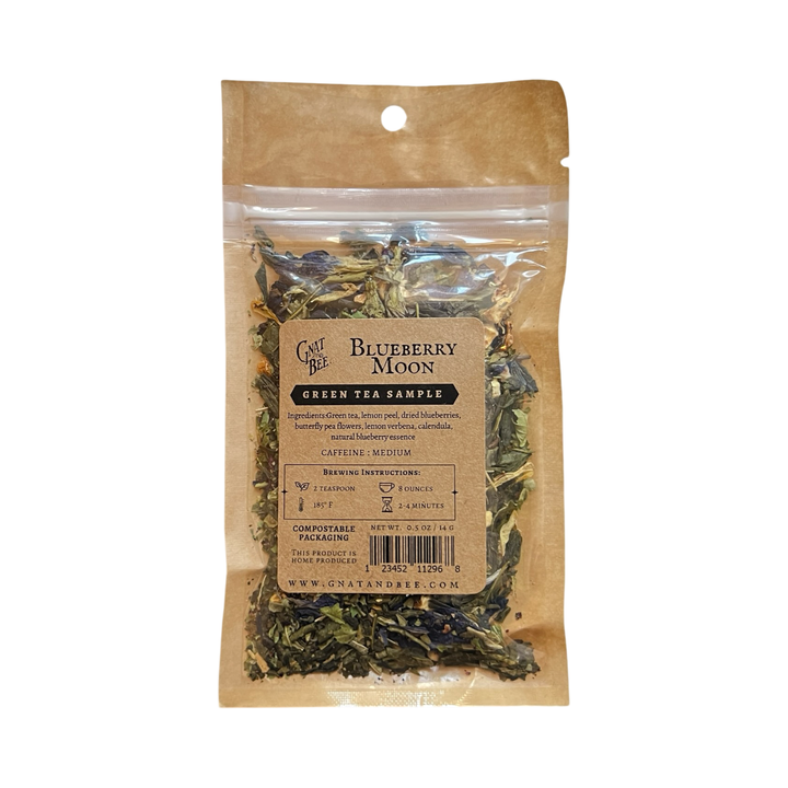 .5 oz kraft pouch of blueberry moon green tea and a branded kraft label with a clear window that displays the dried herbs and flowers.
