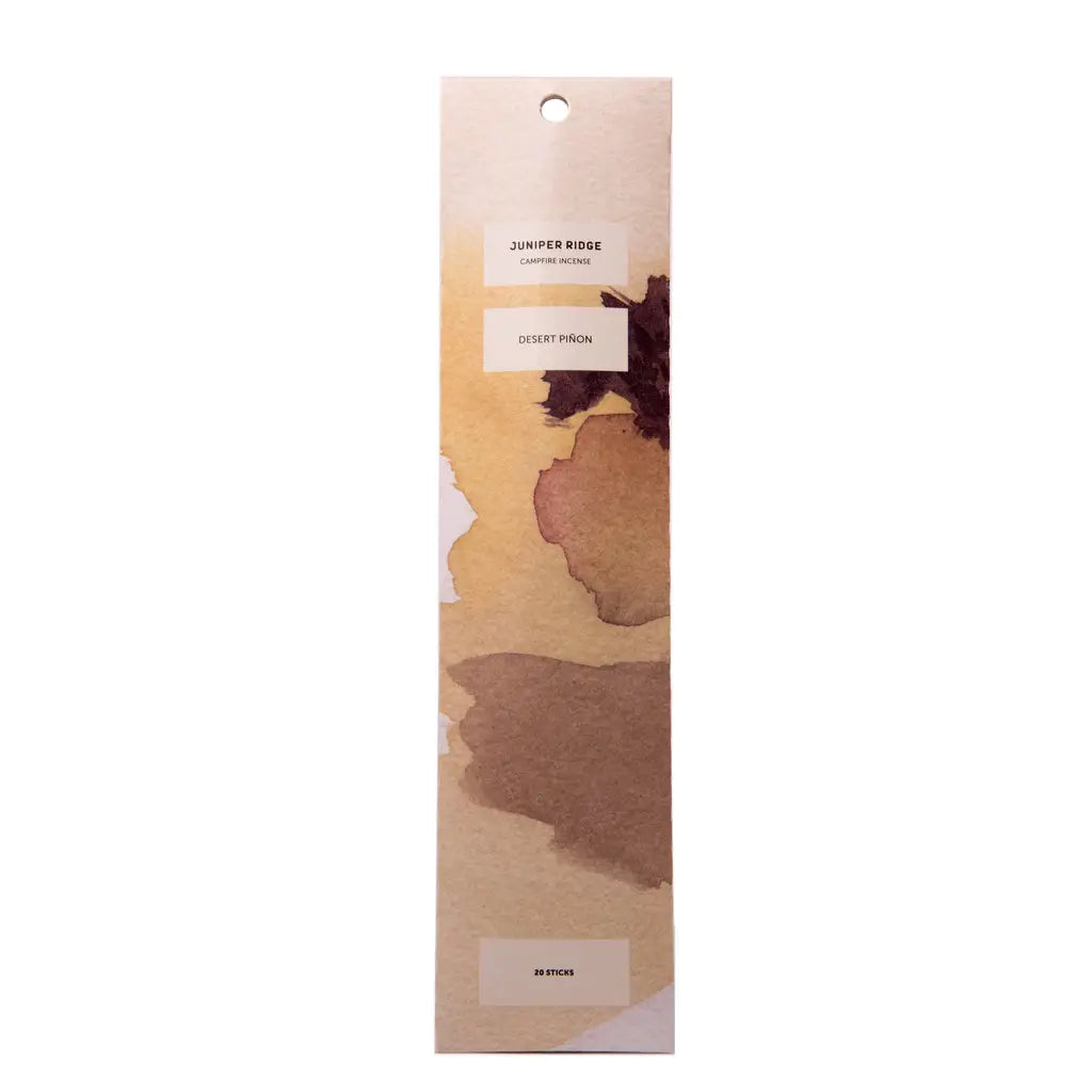 Rectangular package of Juniper Ridge Desert Piñon Campfire Incense, featuring earthy-toned abstract artwork and labeled with "Desert Piñon" and "20 sticks."