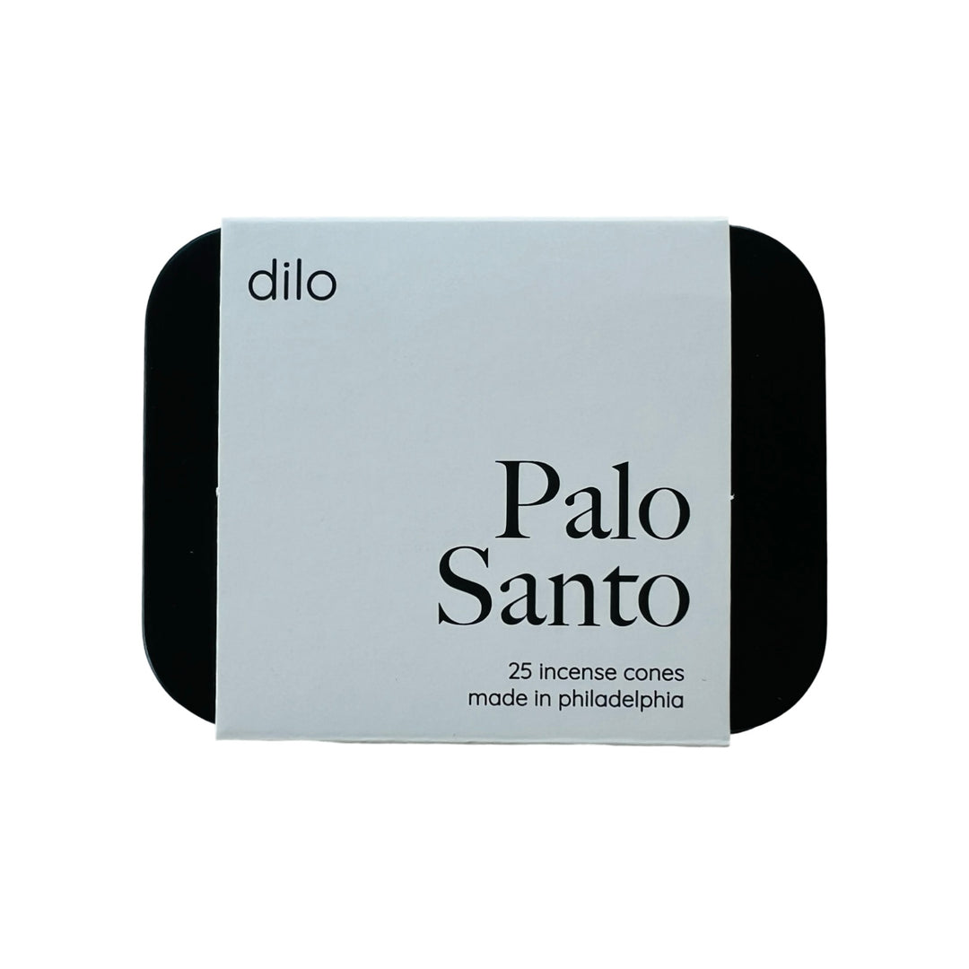 black rectangle tin with a white branded label with the phrase Palo Santo in black lettering.