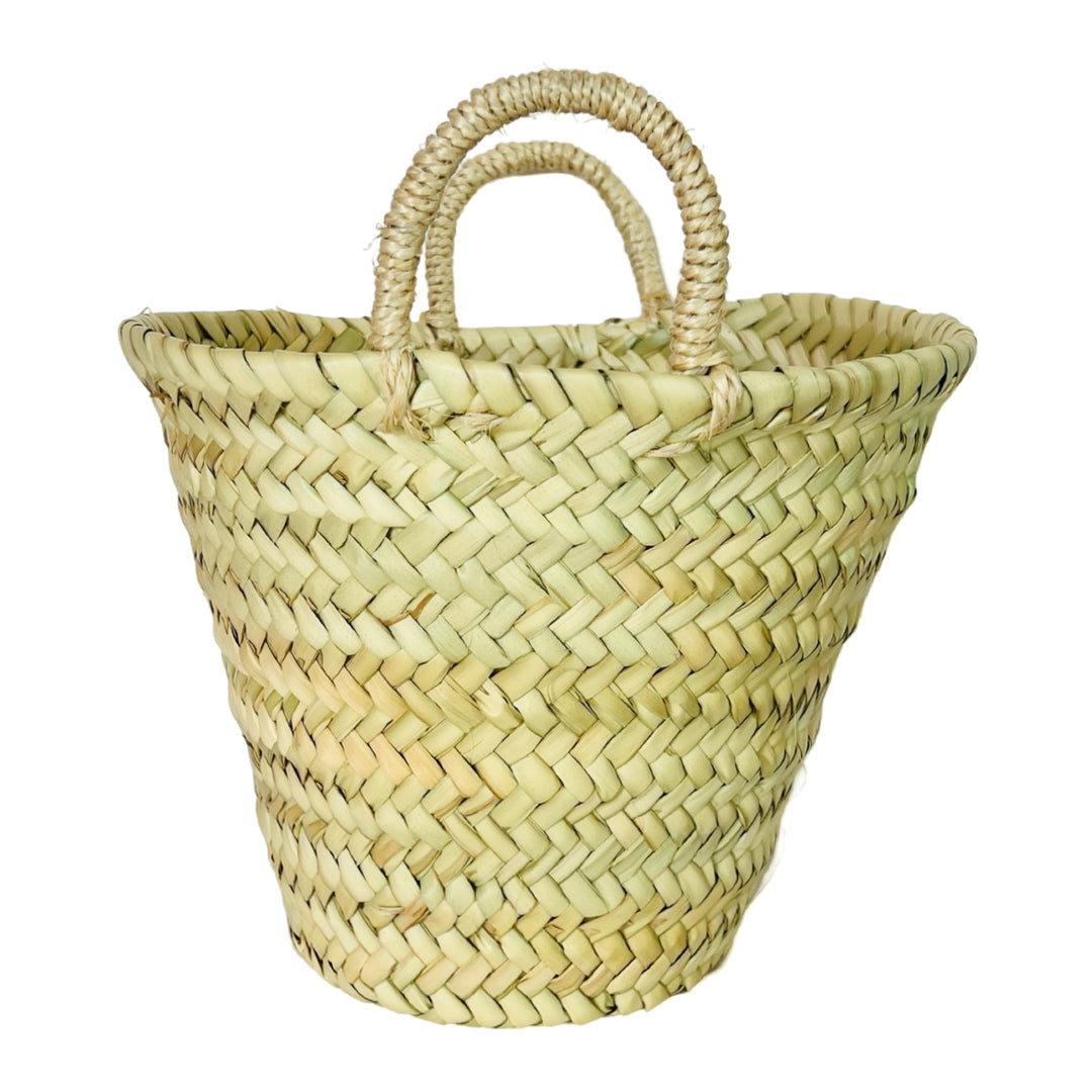 A handwoven straw market basket made from natural palm leaves, featuring a wide, open-top design and sturdy braided handles.