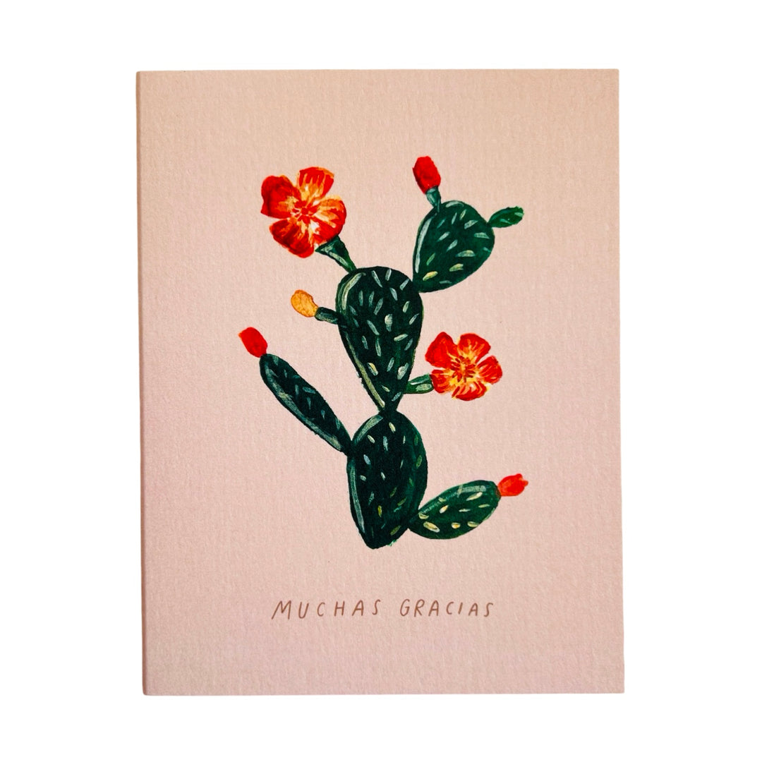 blush greeting card with an illustration of a green cactus and orange/yellow blossoms featuring the phrase muchas gracias in black lettering