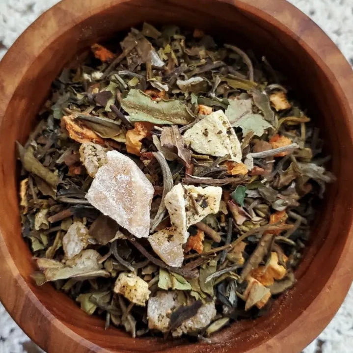 close up view of dried herbs, flowers and fruit in a wooden bowl