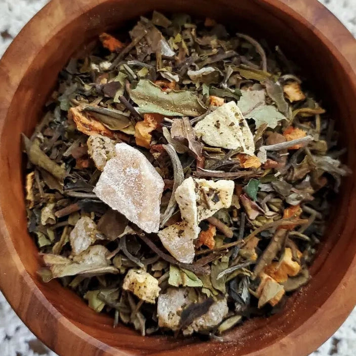 close up view of 2 dried herbs and flowers in a wooden bowl.