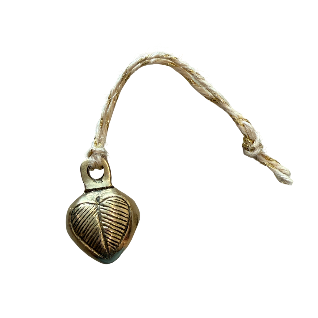 small brass heart-shaped bell with etched detailing and twine loops