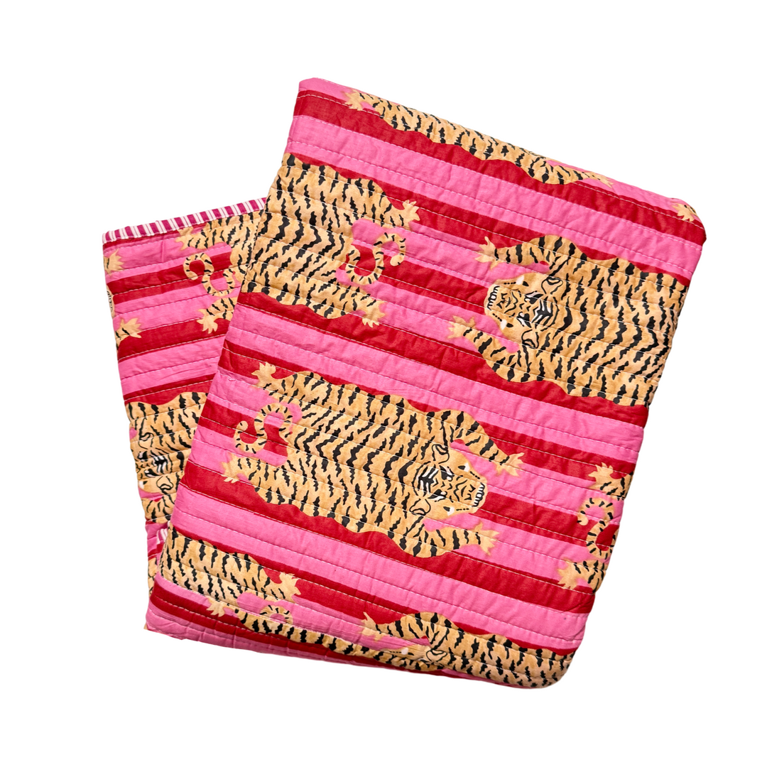 blanket folded in quarters with a red and pink and tiger-striped pattern.