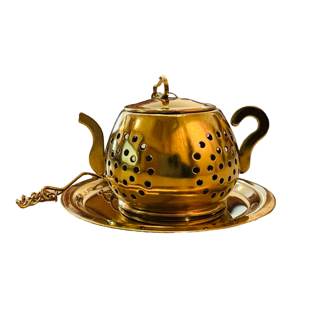 a gold teapot-shaped tea infuser. It features a perforated design and has a small chain