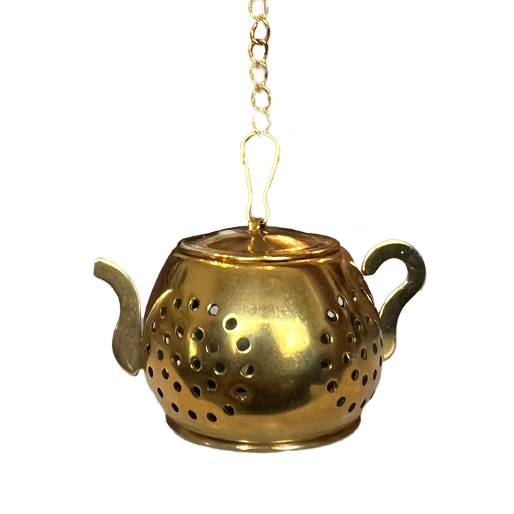 a gold teapot-shaped tea infuser. It features a perforated design and has a small chain
