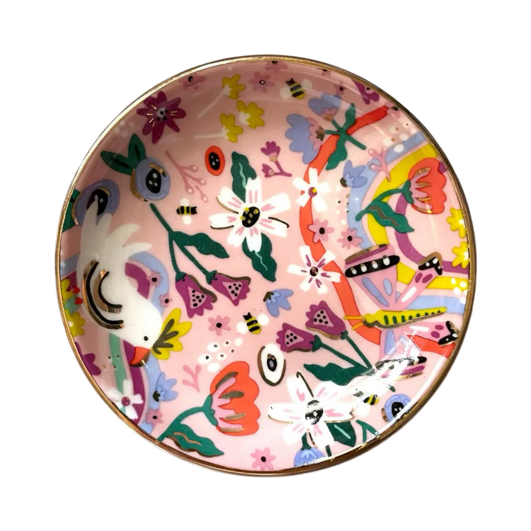 round dish that features a gold edge and a colorful design featurings animals and flowers.