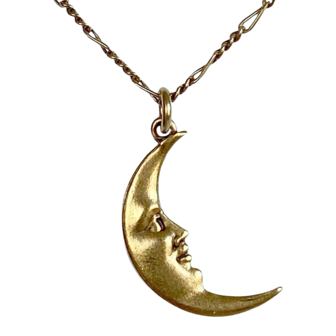 close up of a necklace with a gold crescent moon with a face charm