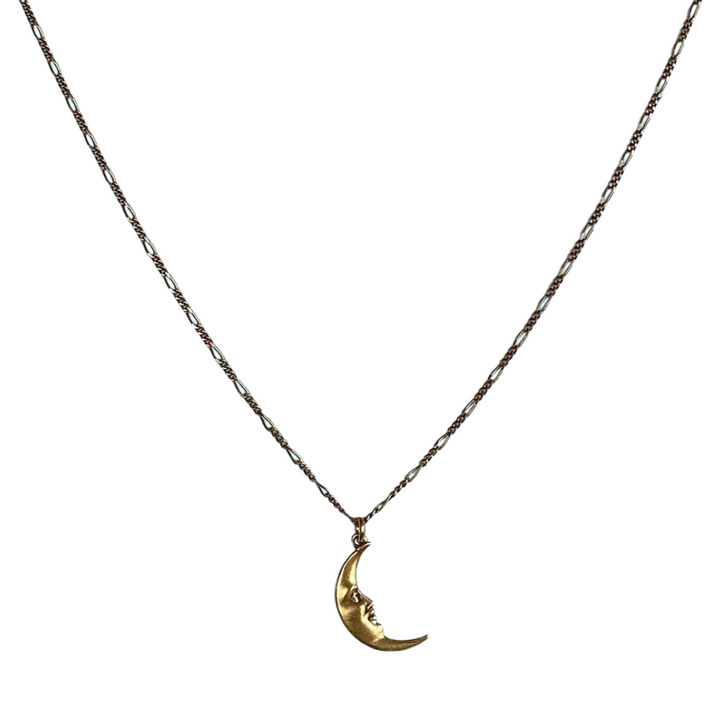 A necklace with a gold crescent moon with a face charm