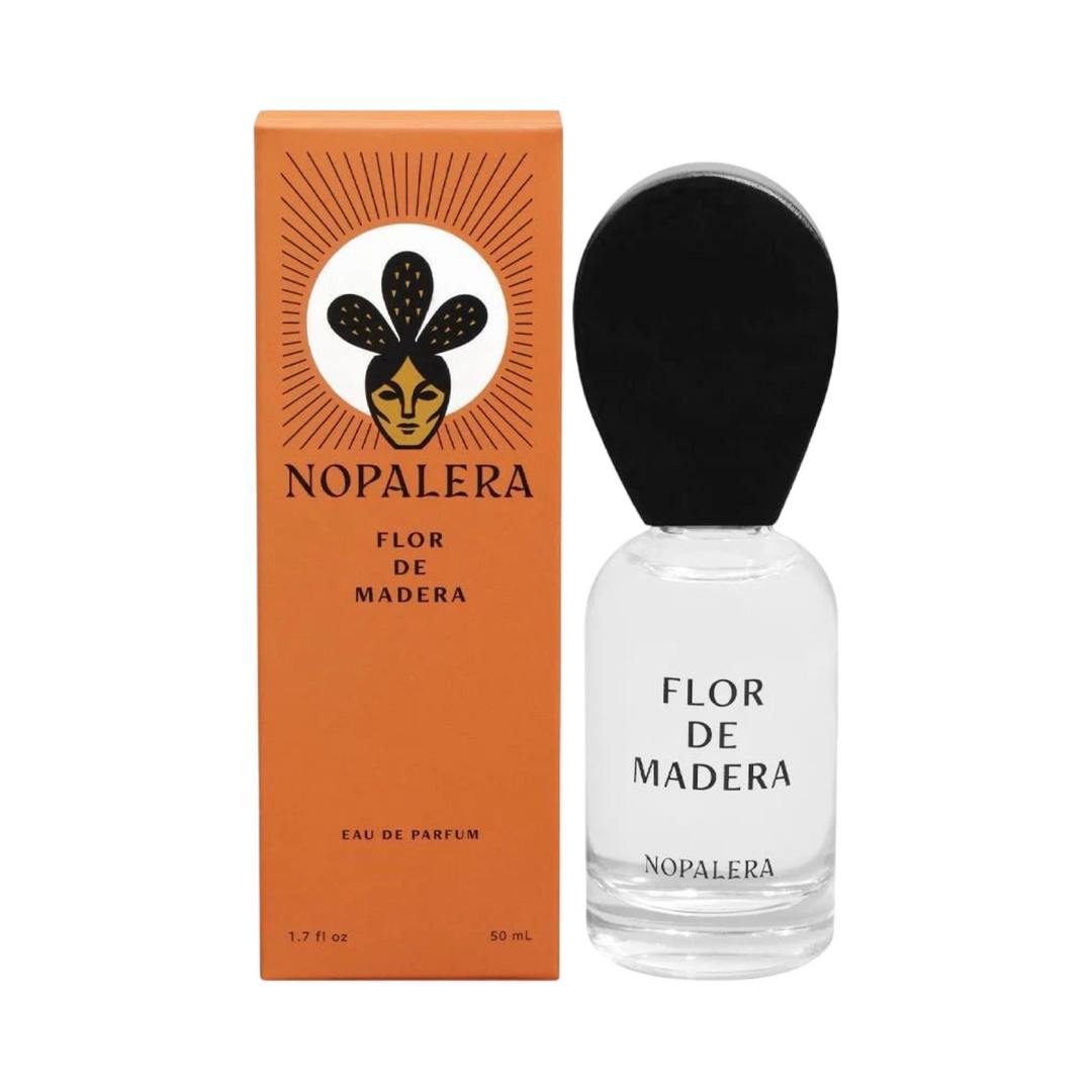 clear 50ml jar with a black top flanked by a orange branded box of Flor De Madera Nopalera perfume