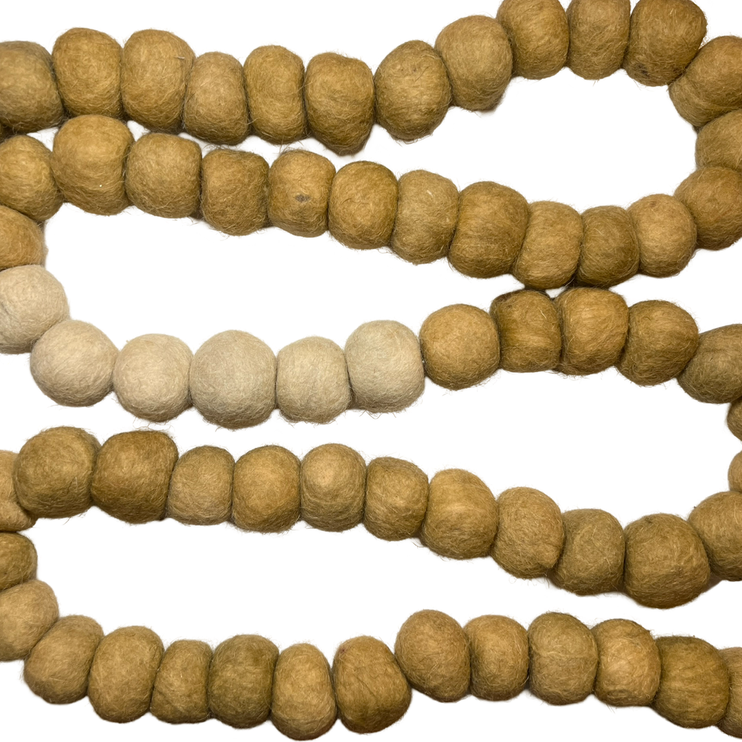 Neutral-toned pom pom garland made of soft felt balls, arranged in a natural gradient of beige and cream hues