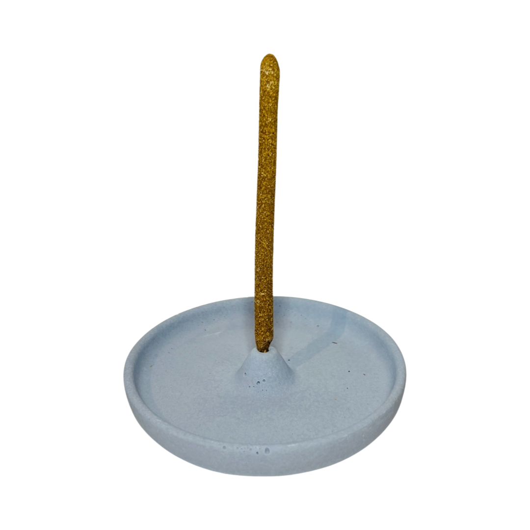 round dusty blue incense holder with an incense stick in it