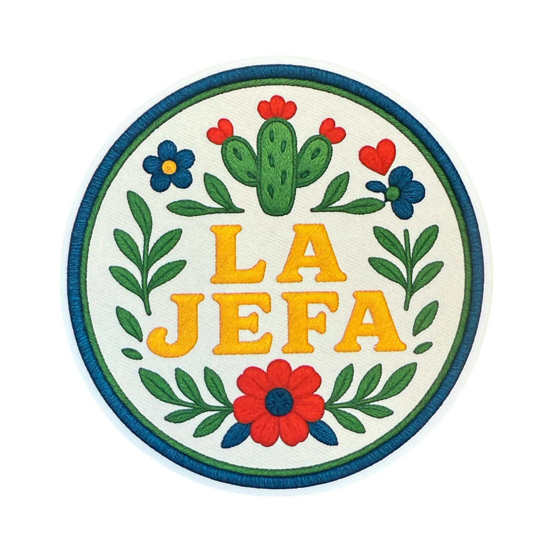 Round sticker with the phrase “La Jefa” in bold yellow letters, surrounded by floral and leafy designs with a nopal cactus at the top, all styled to resemble embroidery.