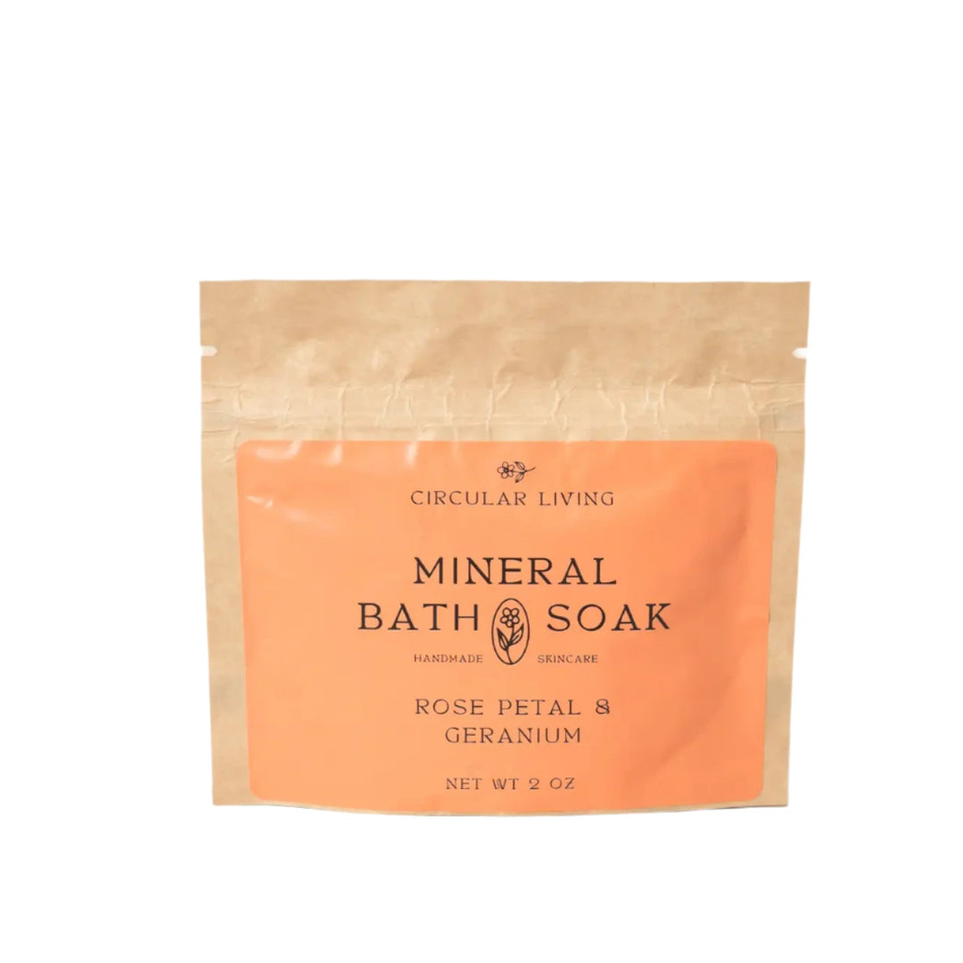 A kraft paper sachet labeled "Circular Living Mineral Bath Soak – Rose Petal & Geranium"