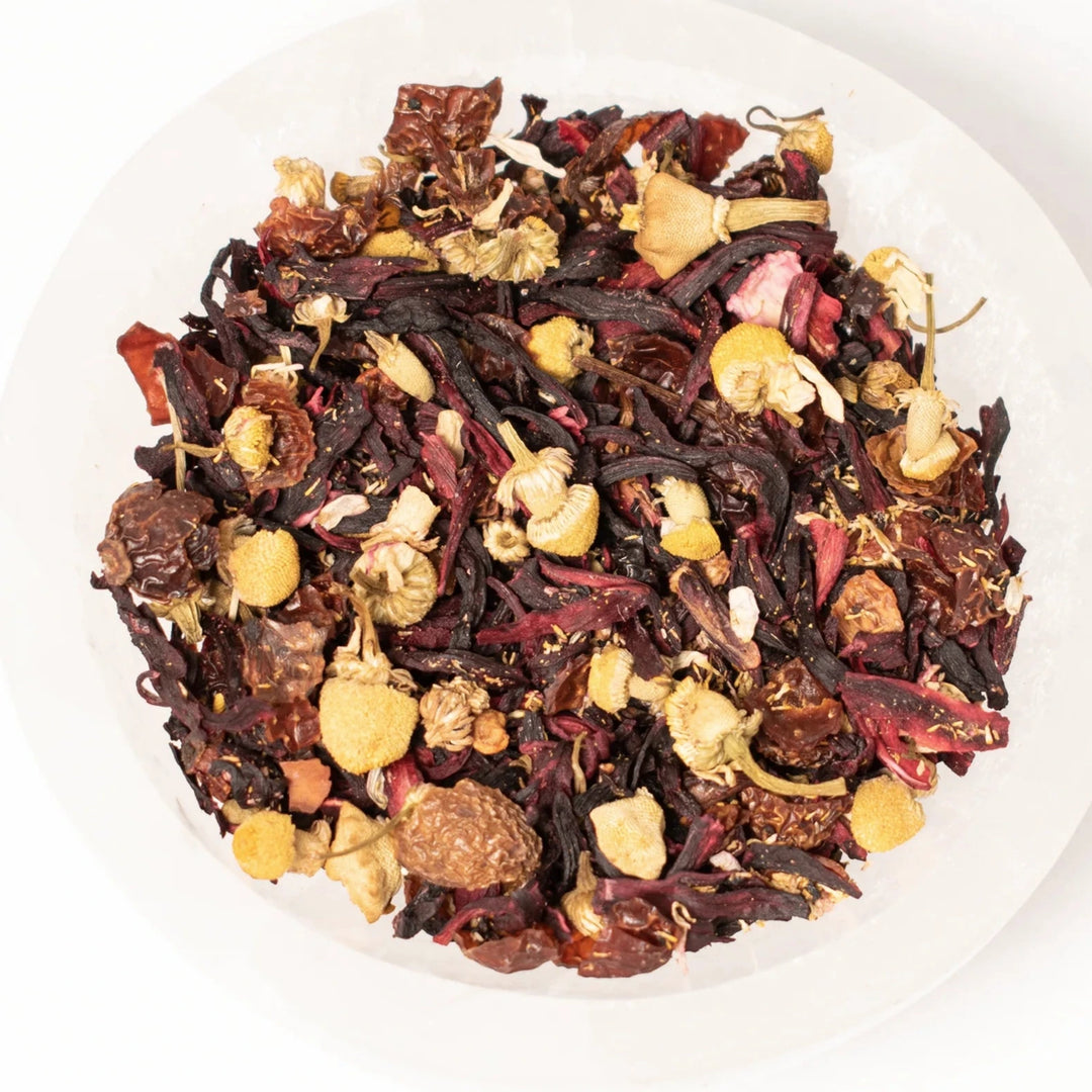 close up view of black tea with dried flowers and fruit in a white bowl