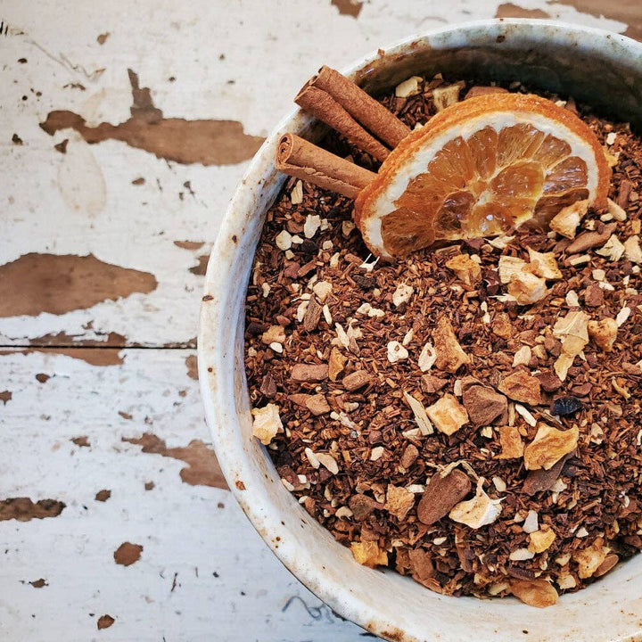 stone bowl of chocolate chai herbal loose leaf tea and features two cinnamon sticks and dried orange slice