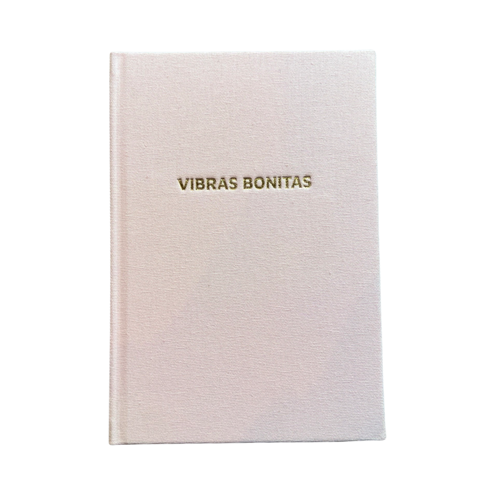 Blush colored hardcover journal with the phrase VIbras Bonitas in gold foil lettering