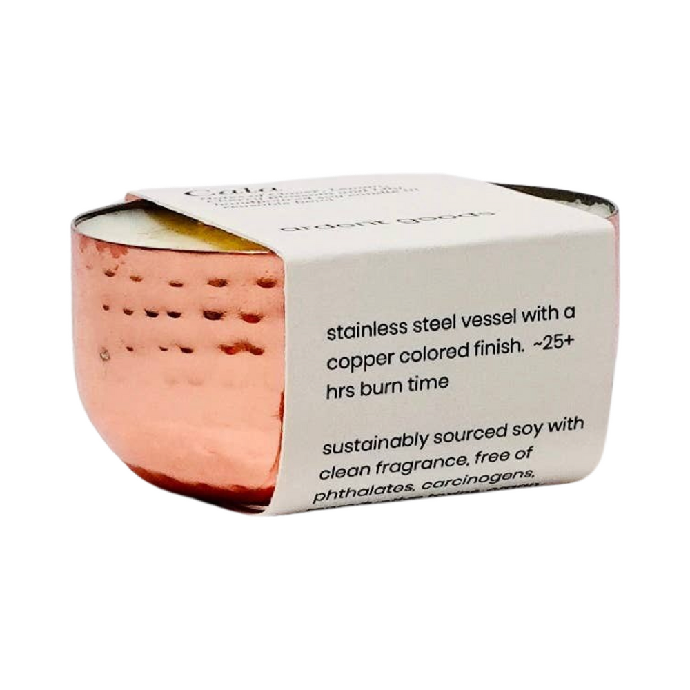 white candle in a copper vessel with white branded packaging. Brand: Ardent Goods