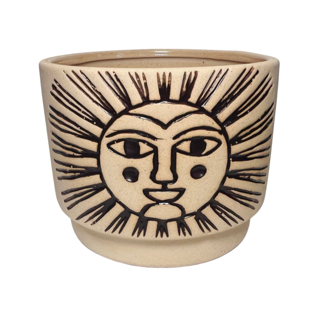 Beige ceramic cachepot with with an engraved design of a sun filled in with dark brown.