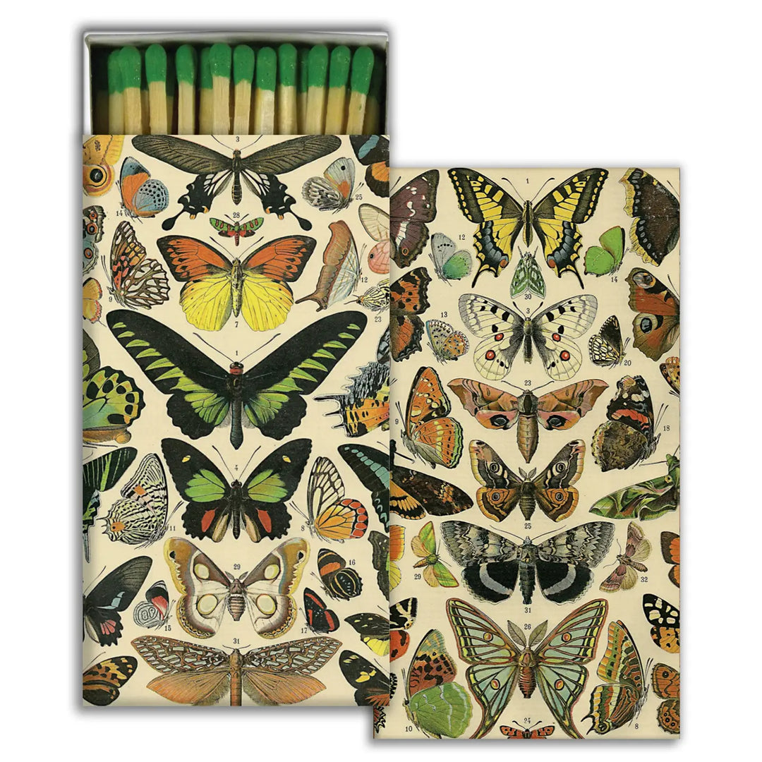 A decorative matchbox featuring a vintage-style design of colorful butterflies and moths in various sizes and patterns. The box is open, revealing green-tipped matches neatly arranged inside.