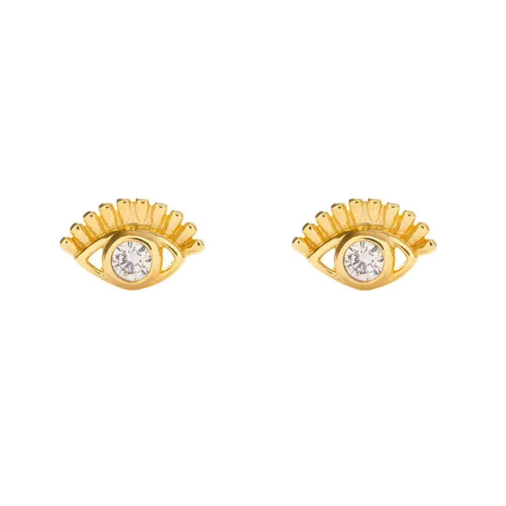 A pair of gold eye-shaped stud earrings featuring a central clear crystal and delicate eyelash detailing, set against a white background. The design combines elegance with a symbolic, mystical charm.