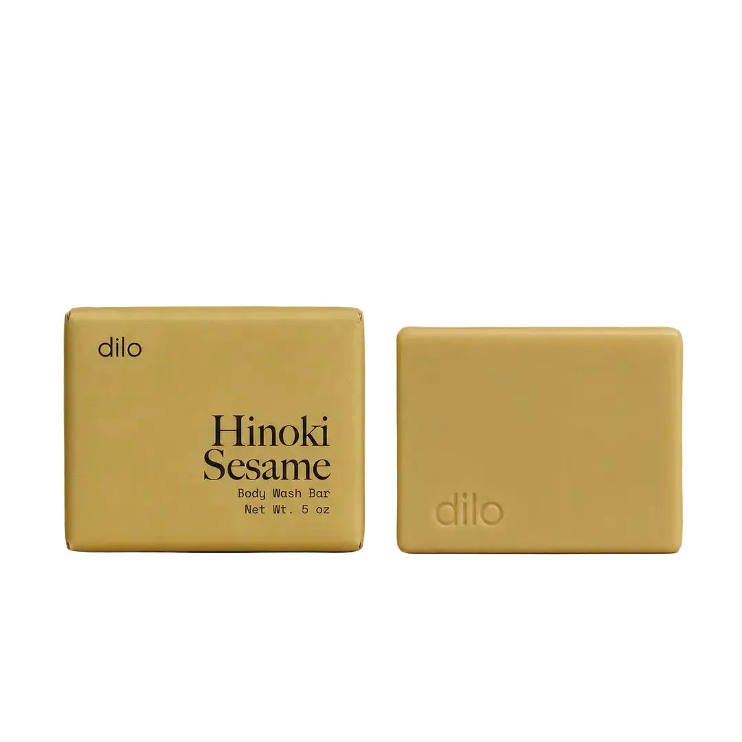 Dilo Hinoki Sesame body wash bar with golden yellow packaging shown alongside the unwrapped soap bar.