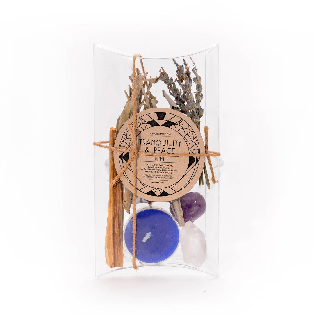 clear box with branded circle brown label and contains dried herbs and flowers, palo santo, crystals and blue candle