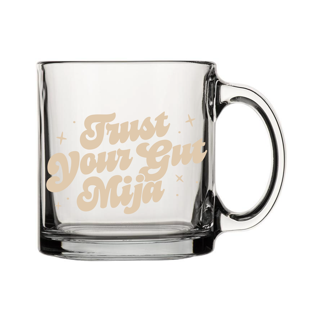 Clear Glass mug with the phrase "Trust Your Gut Mija" in ivory, bold, script  lettering with star accents