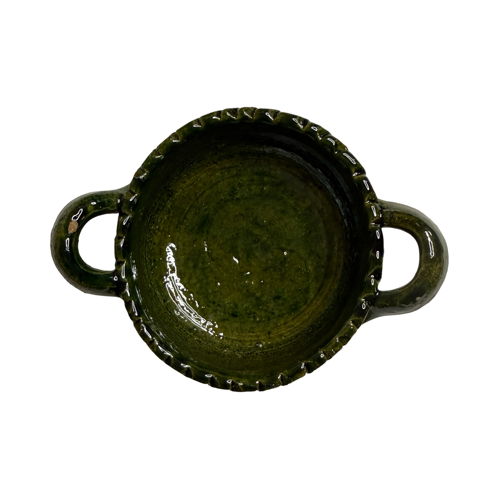 top view of a small round dish with handles featuring a green glaze.