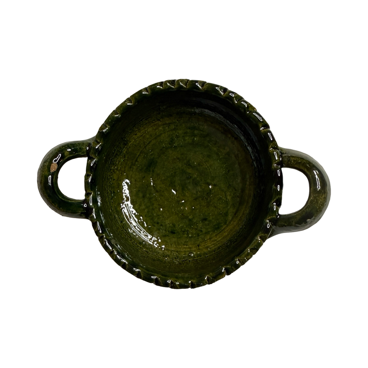top view of a small round dish with handles featuring a green glaze.