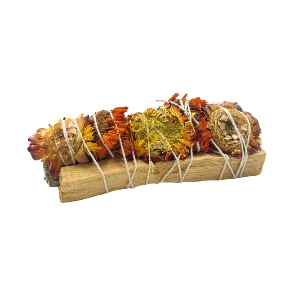Hand-tied sage bundle bound with a Palo Santo stick and accented with bright orange strawflower/sinuata blooms, wrapped in white string.