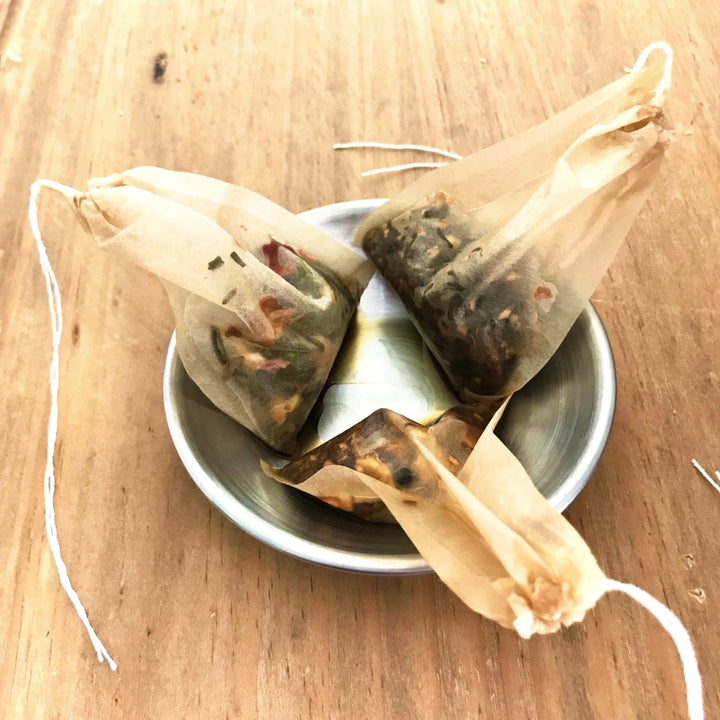 image of three tea saschets filled with loose leaf sitting in a metal bowl.