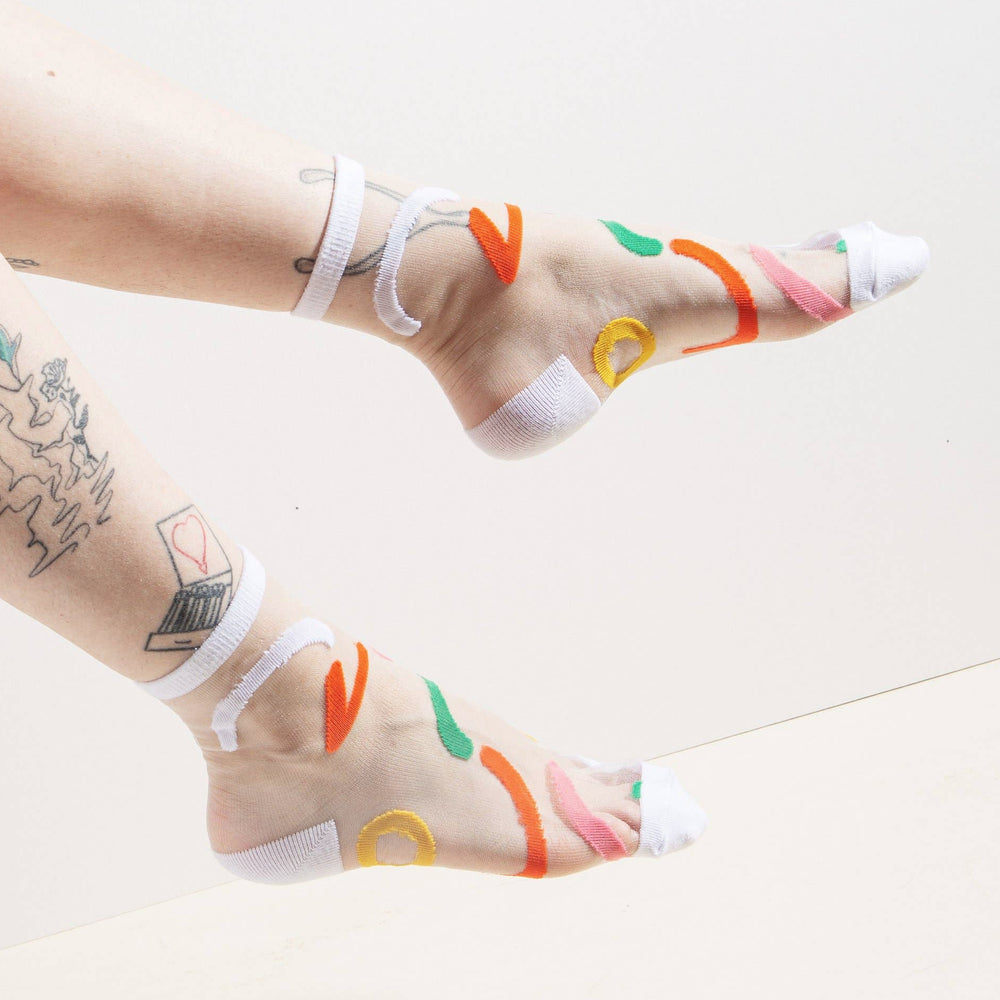 feet wearing a pair of sheer socks featuring a contemporary, abstract design and bold yellow accents