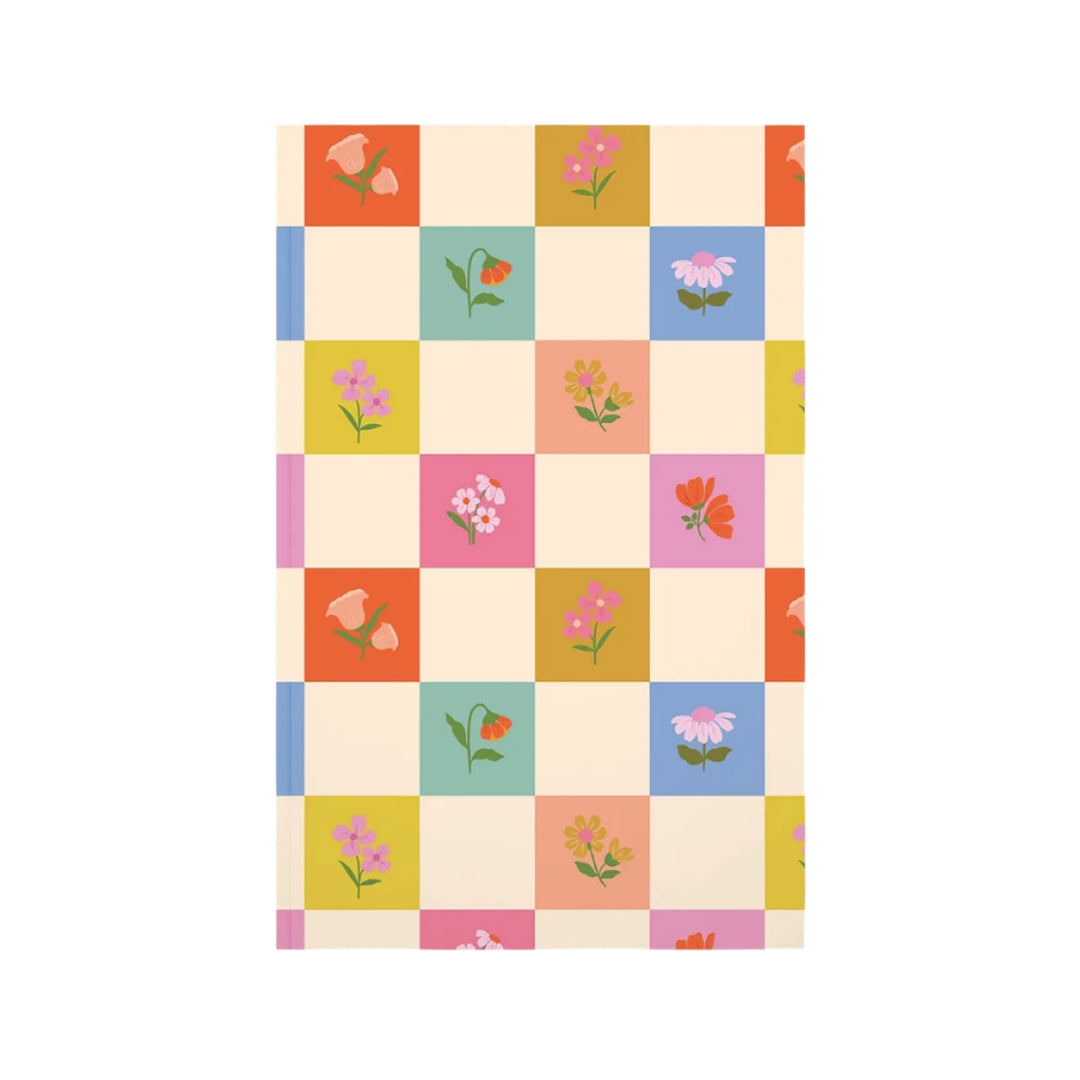 A checkered journal cover with alternating cream and colorful squares, each adorned with small, delicate flowers in shades of pink, orange, yellow, and green