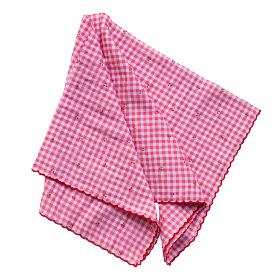 A pink and white gingham cotton scarf with small cherry embroidery and red scalloped edges.