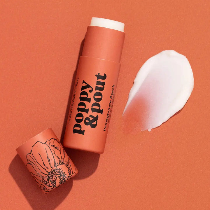 Tube of lip balm labeled “poppy & pout” with matching cap and a swatch of balm beside it.