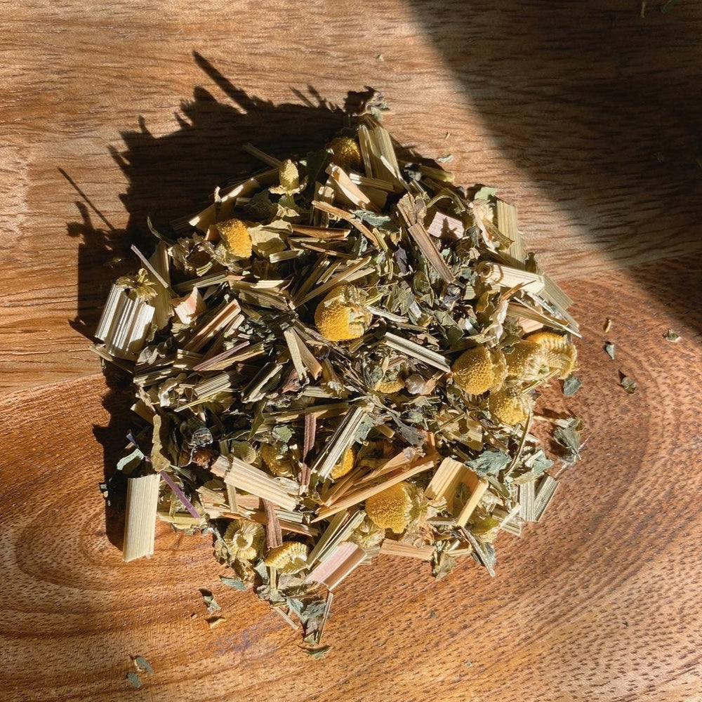 pile of dried Tulsi Holy Basil, Lemon Balm, Lemongrass, Chamomile on a wooden surface