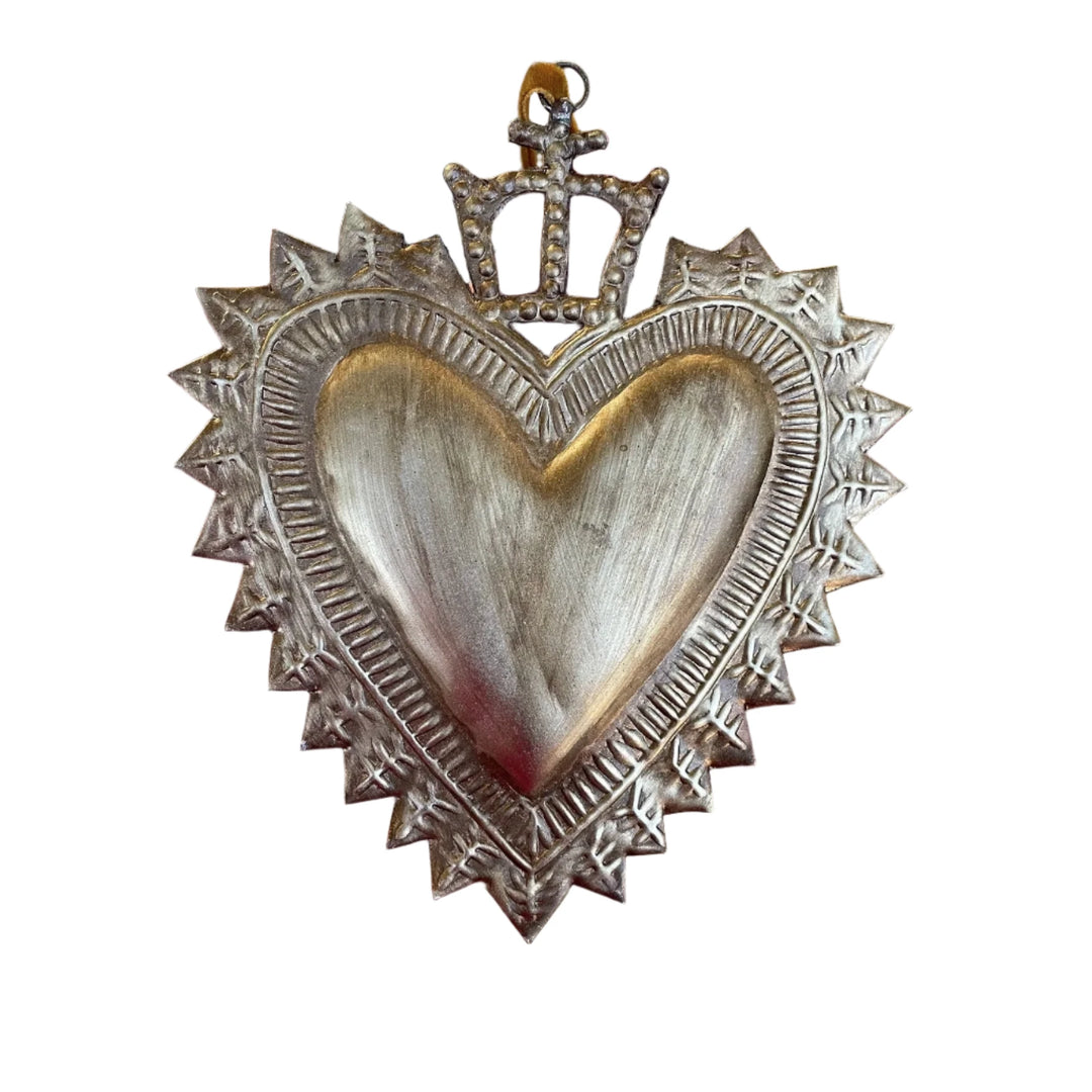 A silver-toned sacred heart ornament with a textured radiant border and a detailed crown on top, symbolizing love and devotion.