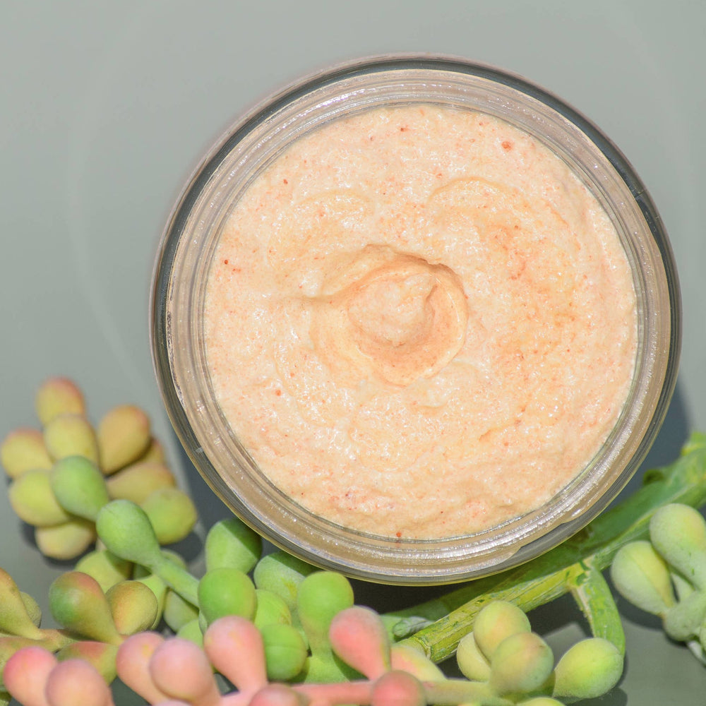 top view of an open jar of pink salt scrub with succulents as decor. Brand: UnTamed Naturals