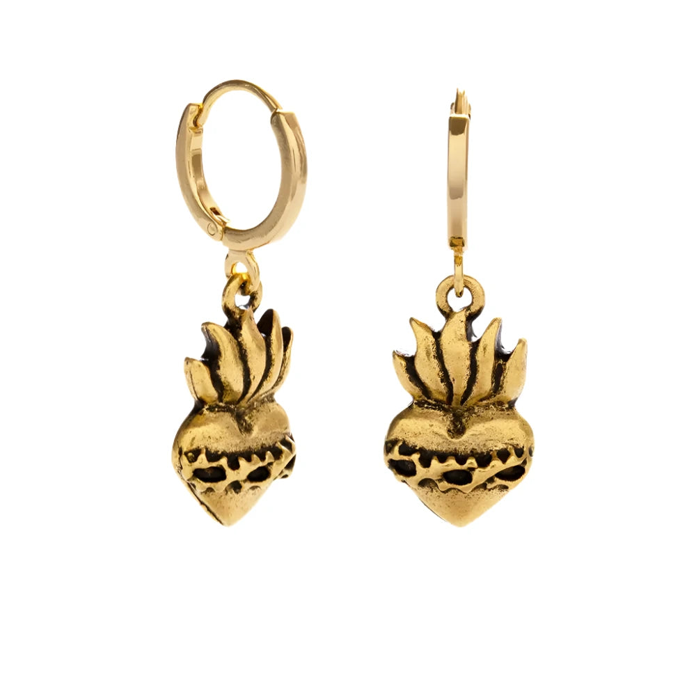 A pair of gold-tone Corazon Sagrado Huggie Hoop earrings featuring intricately detailed sacred heart charms with a vintage-inspired finish