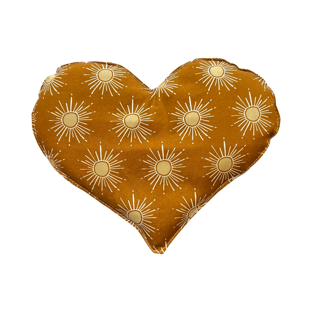 heart shaped eye pillow with yellow suns on a caramel background.