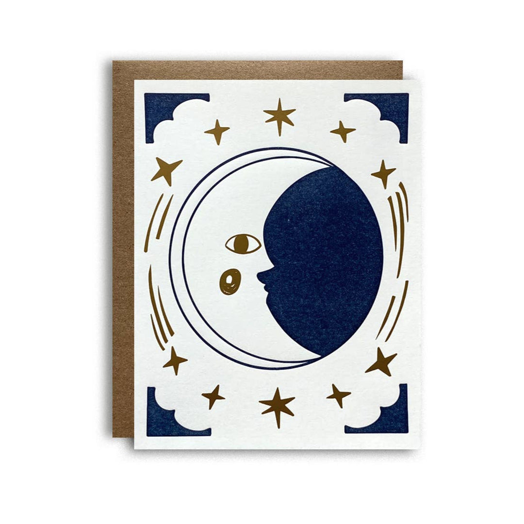 white card with brown envelope featuring an illustration of a crescent moon with eyes and surrounded by stars in gold and blue corners