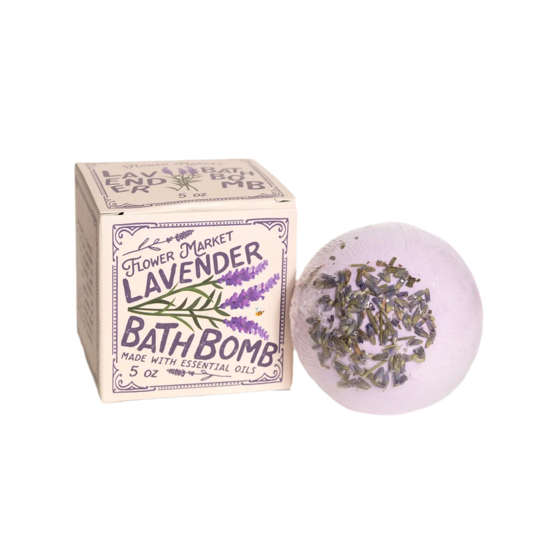 Round lavender bath bomb with dried flowers alongside a branded box.