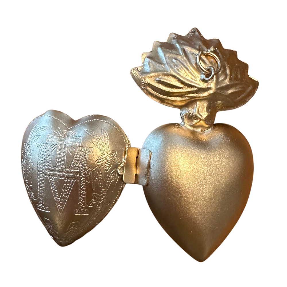 gold sacred heart ornament opened up with an etched design on one half of the heart